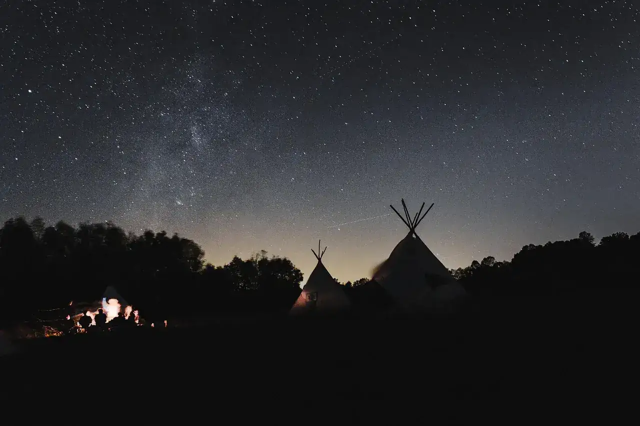 Desert camp silhouetted under a star-filled sky