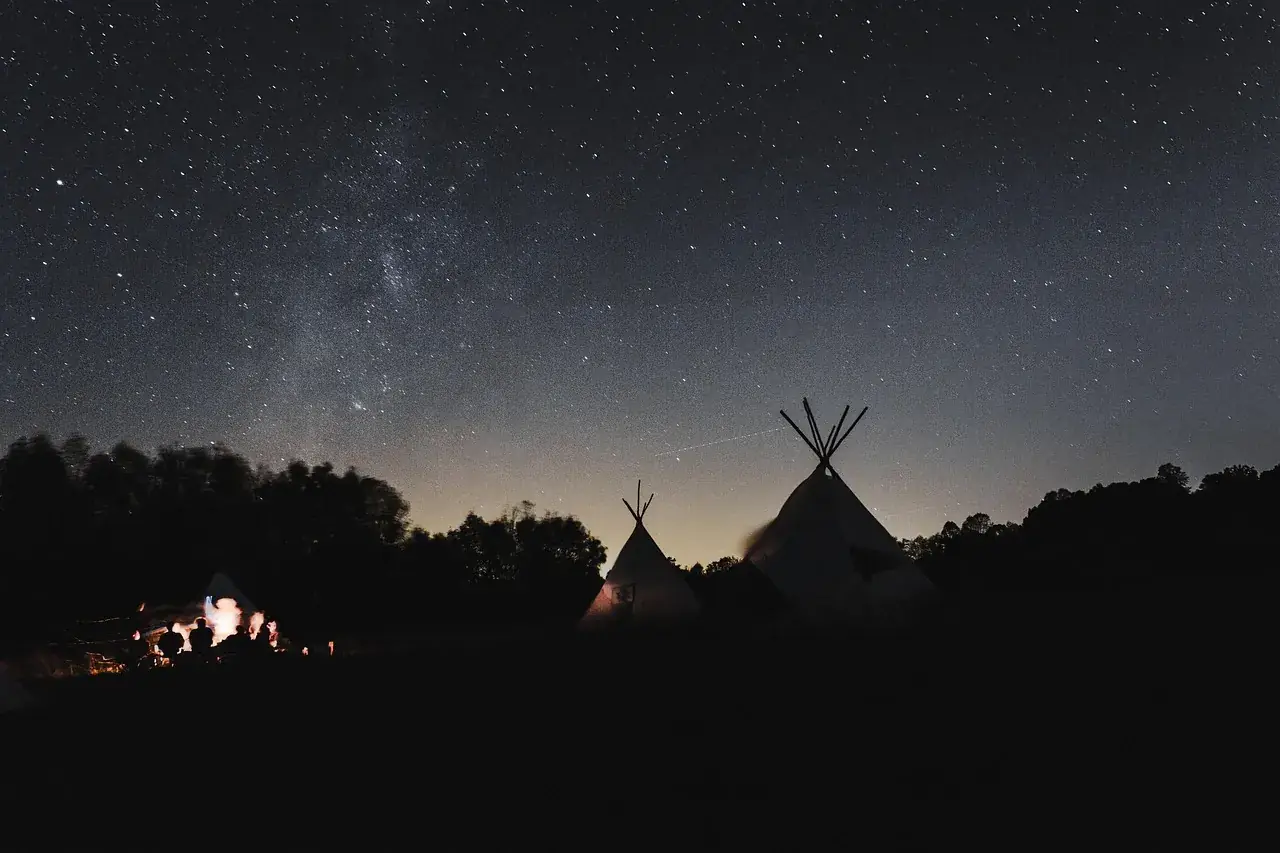 Desert camp silhouetted under a star-filled sky