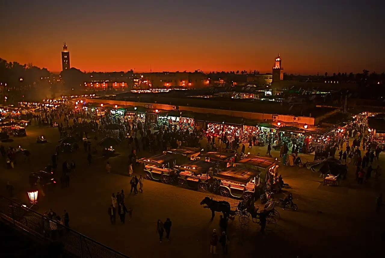 Puestos de comida y multitud iluminados por la noche en la plaza Jemaa el-Fnaa de Marrakech