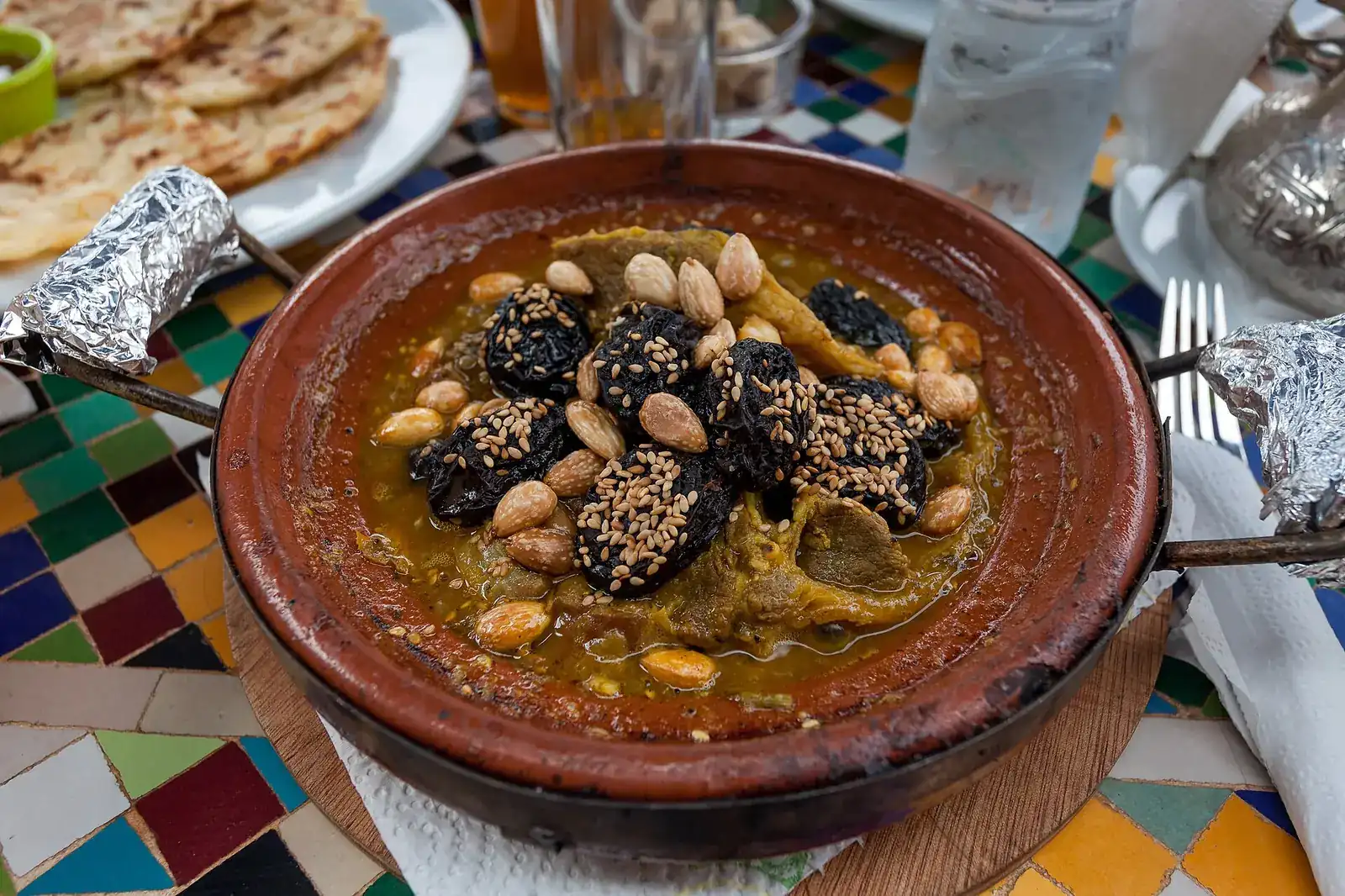 Tajín marroquí de carne con ciruelas pasas, almendras y sésamo sobre una mesa de azulejos