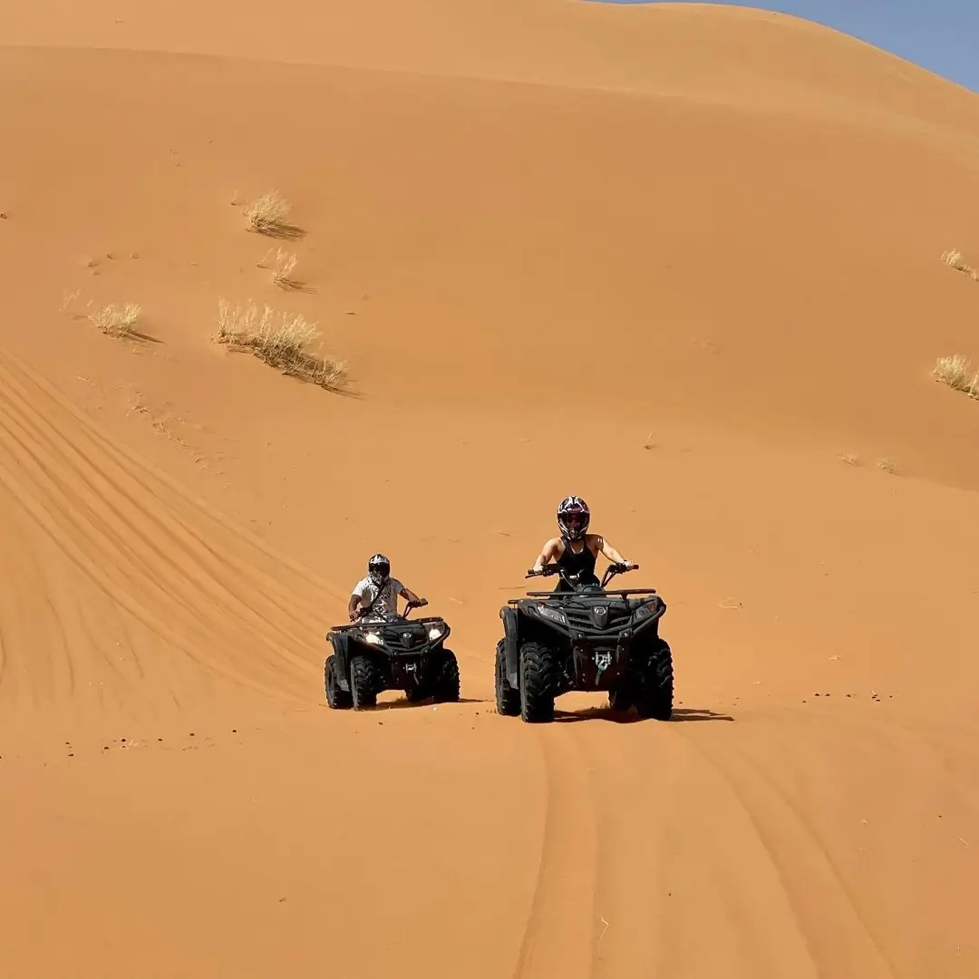 Two quad bike riders crossing the Sahara dunes near Merzouga
