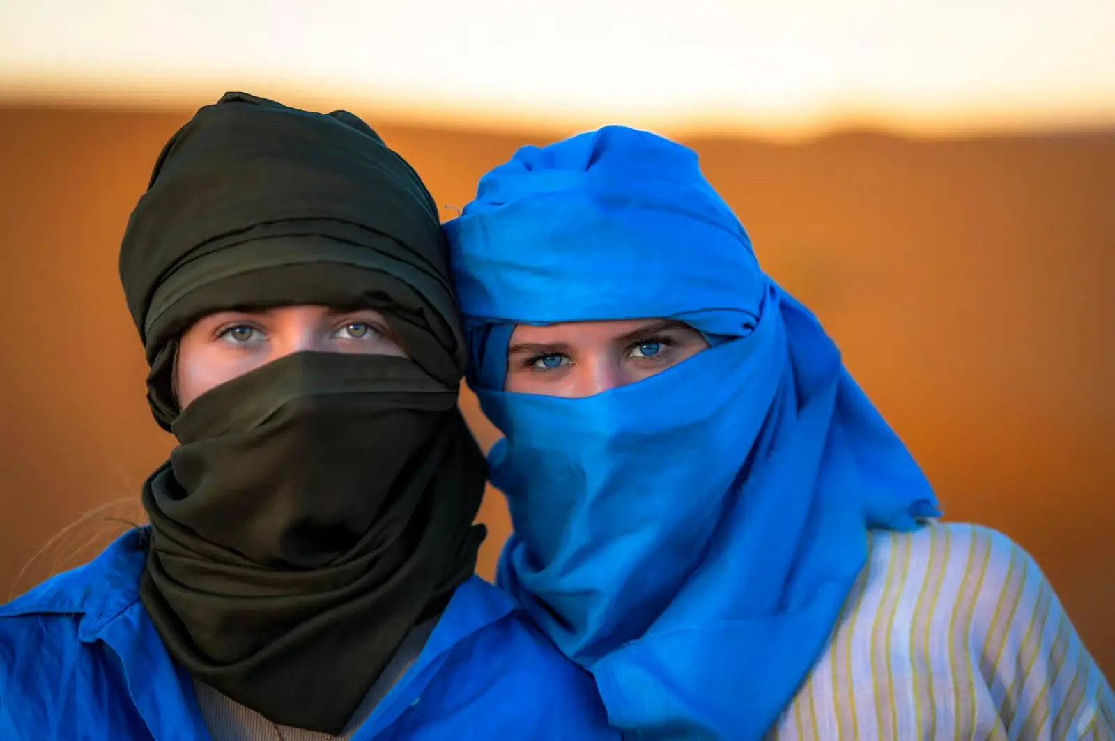 Pareja con turbantes tradicionales azul y negro al atardecer en el Sáhara