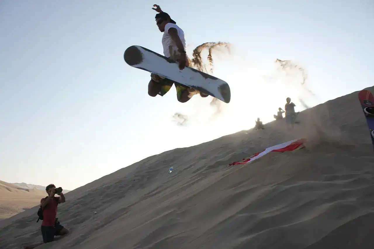 Sandboarder launching off the crest of a dune