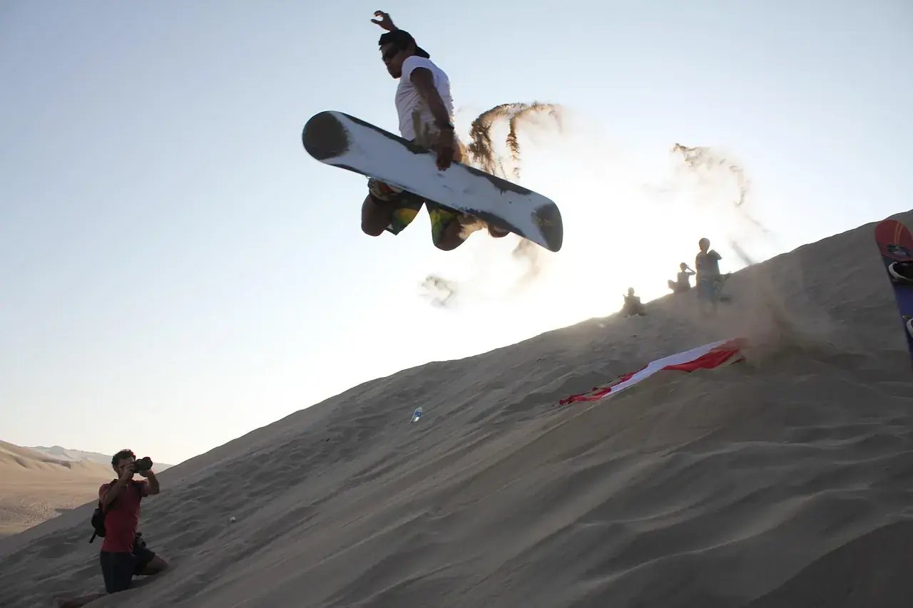 Sandboarder launching off the crest of a dune