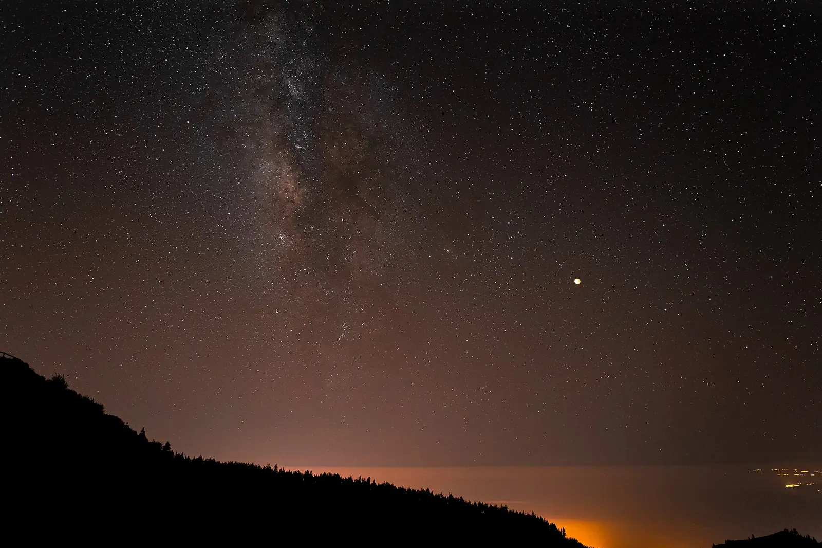 La Vía Láctea y un eclipse lunar bajo el cielo con calima del desierto