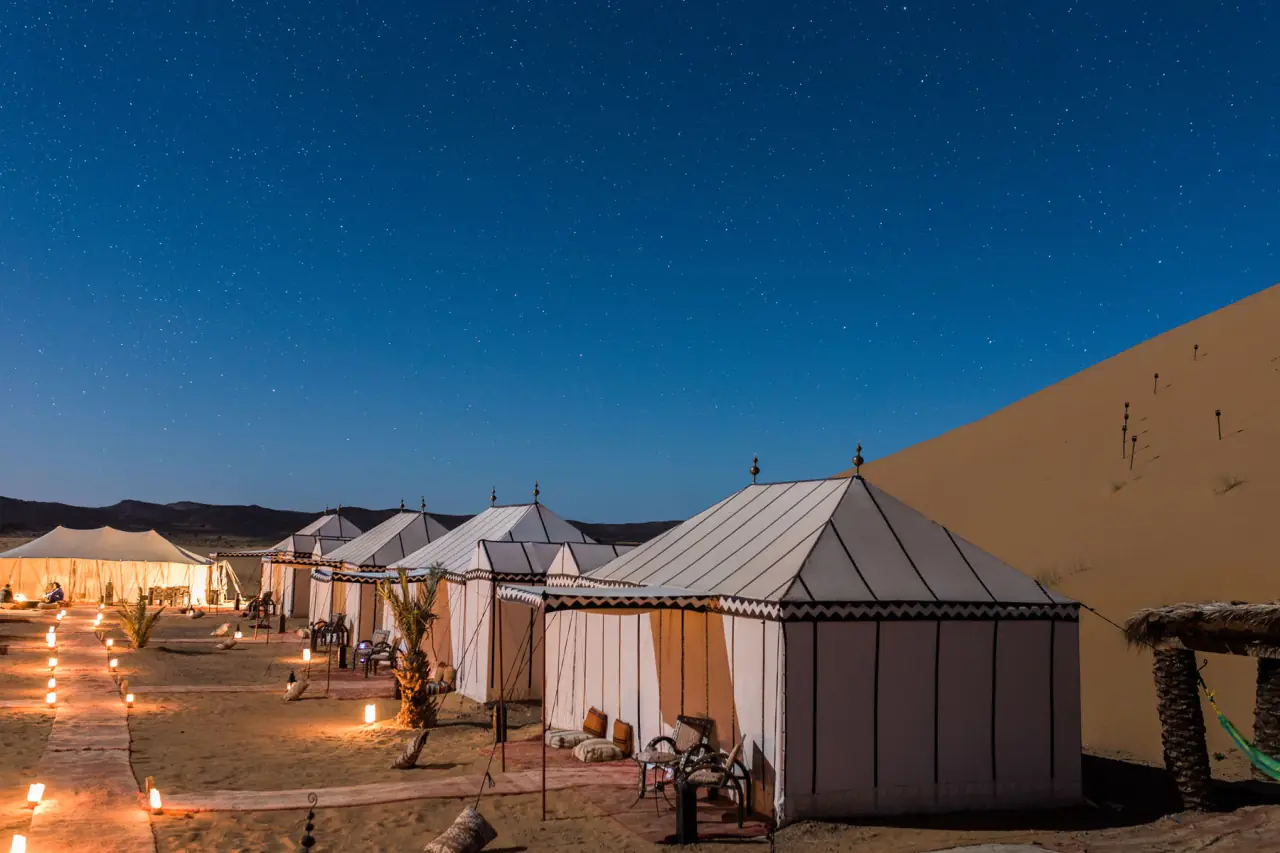 Row of desert tents lit by lanterns under a night sky