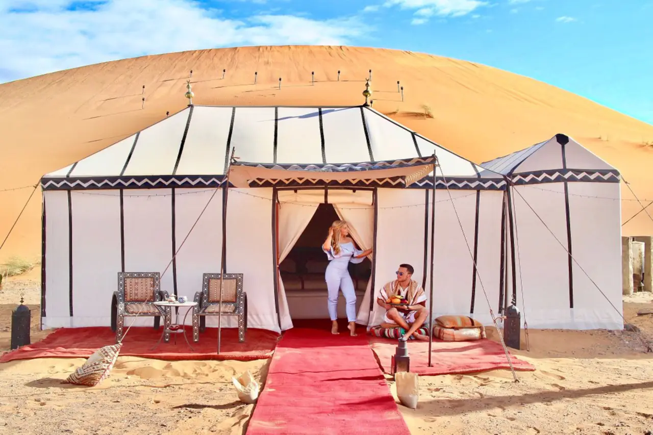Guests relaxing at the entrance of a white desert tent