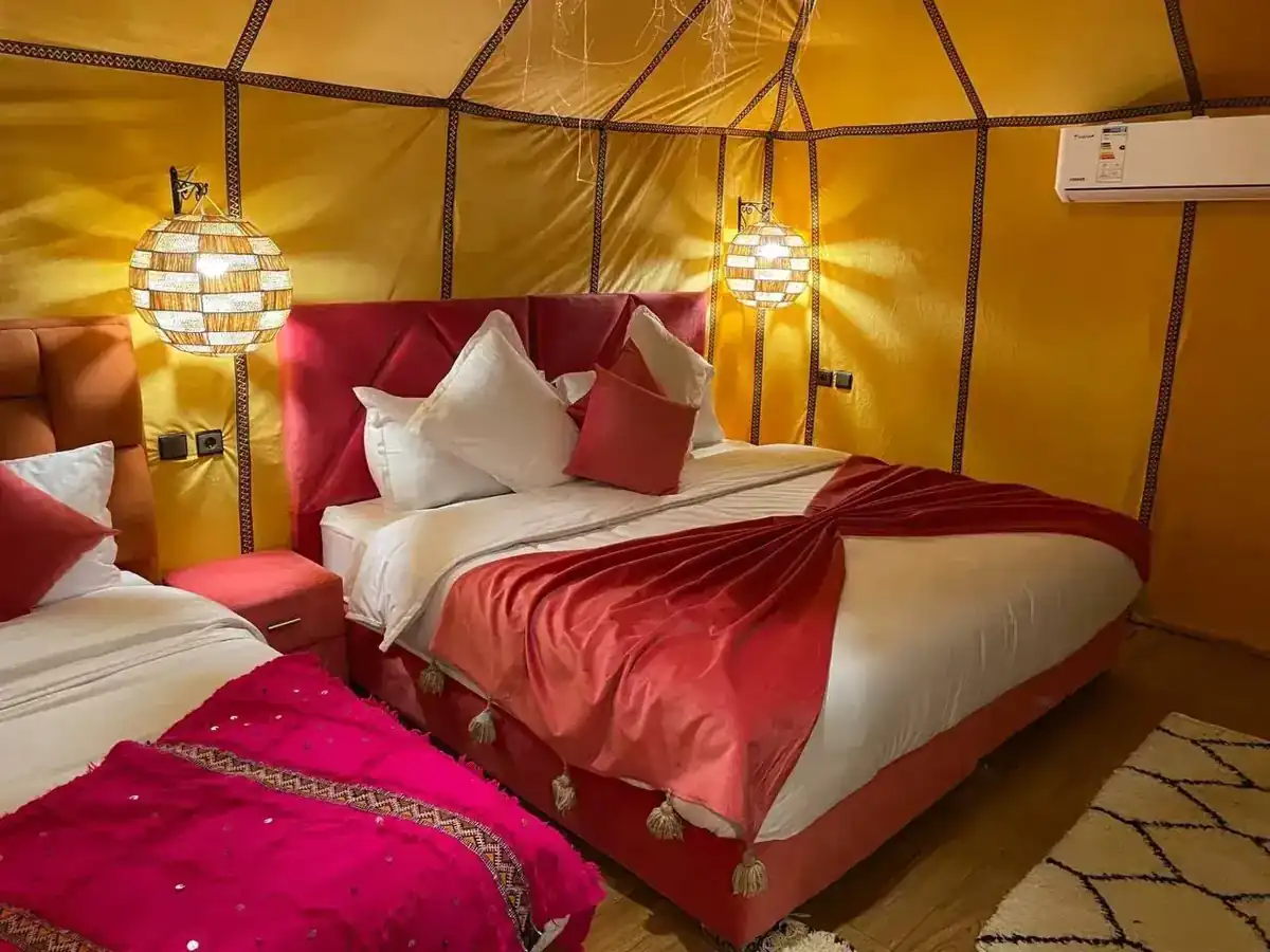 Double luxury tent interior at Merzouga Glamping with a large bed and warm lanterns
