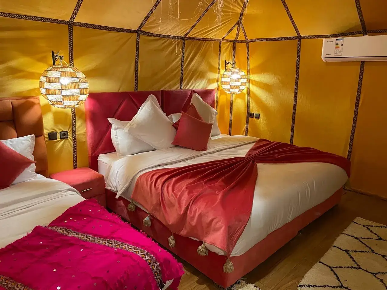 Double luxury tent interior at Merzouga Glamping with a large bed and warm lanterns
