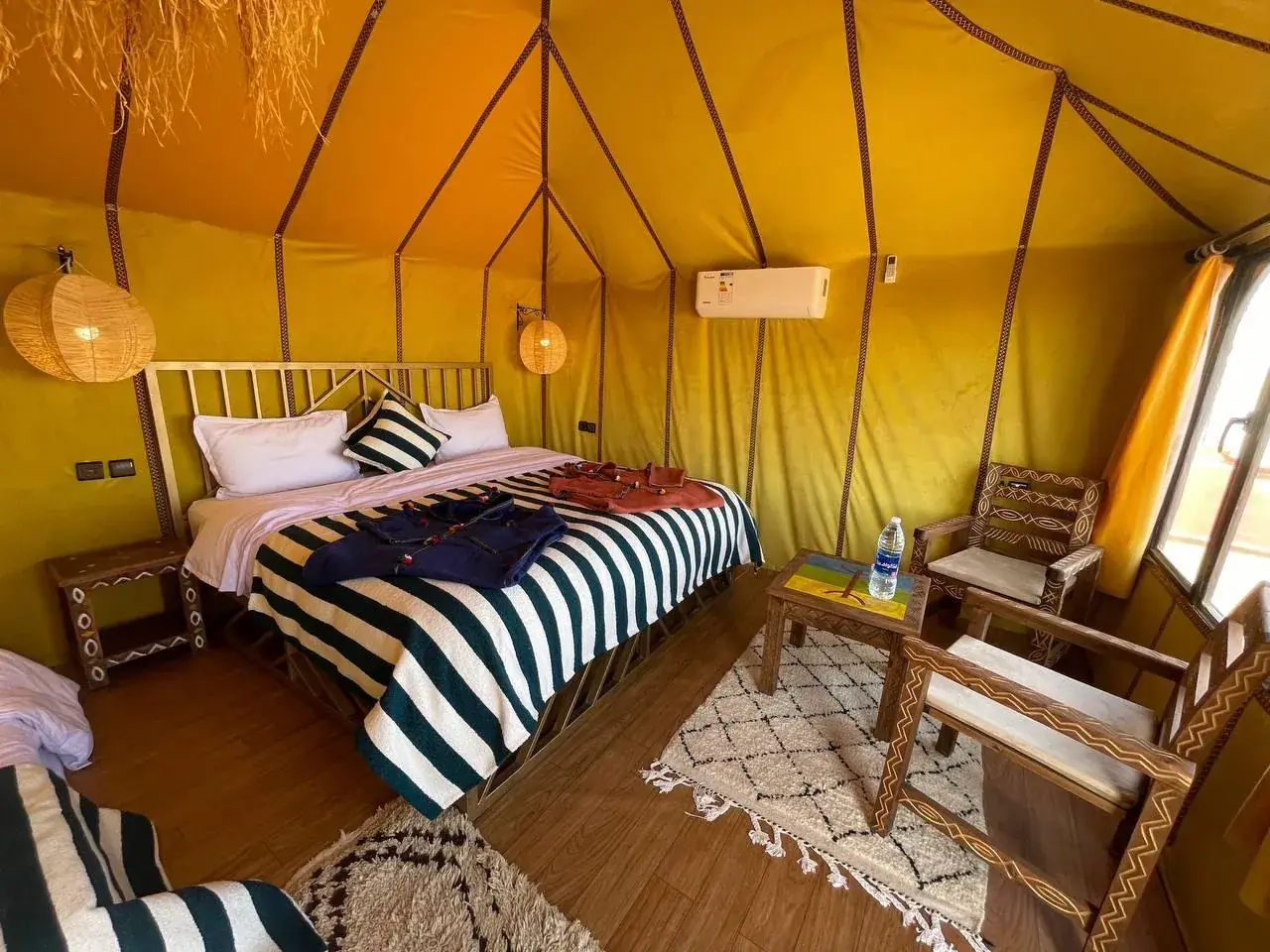 Interior of a single luxury tent at Merzouga Glamping with a made bed and Berber rug
