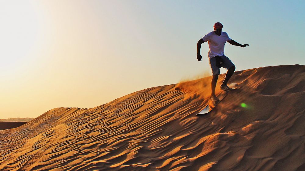 A person going down a sand dunes on a sandboard